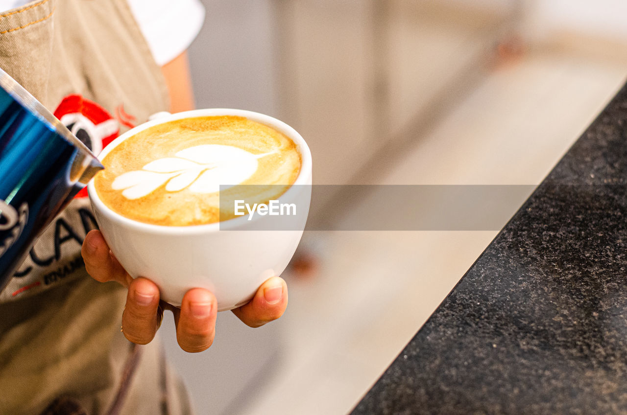 MIDSECTION OF COFFEE HOLDING CUP OF CAKE