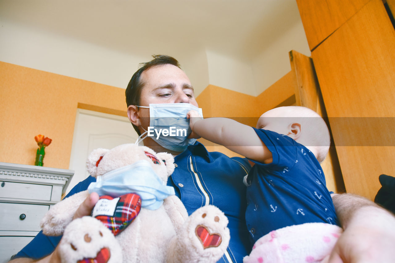 Father holding daughter and stuffed toy at home
