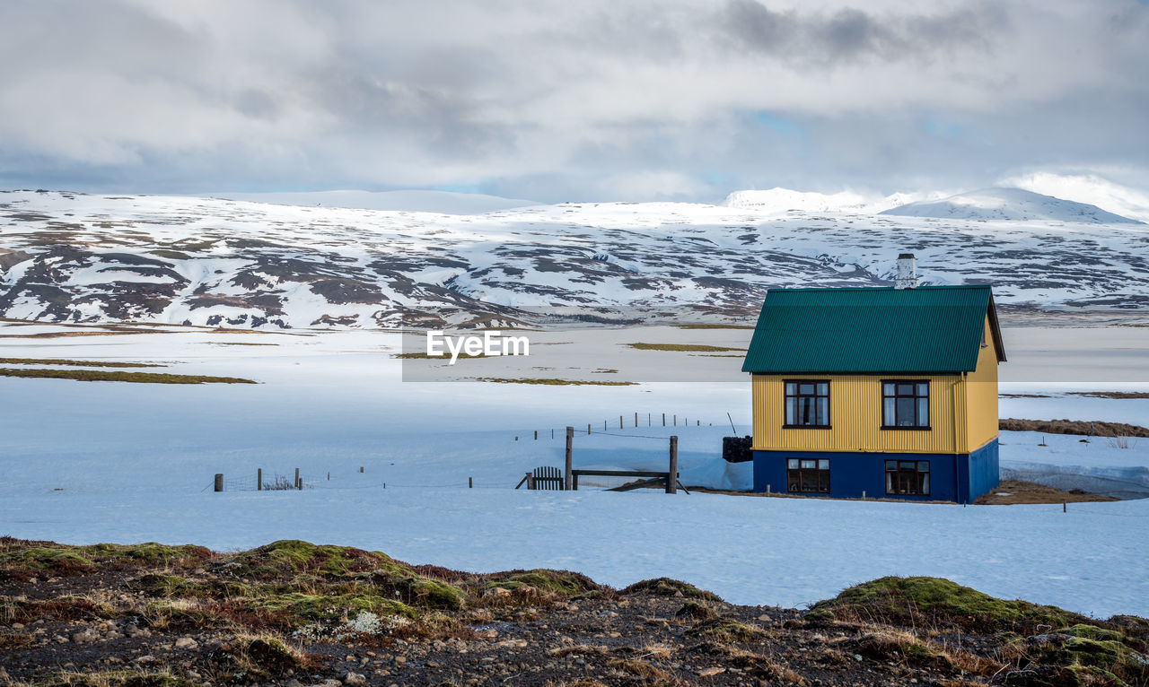 snow, cold temperature, winter, landscape, water, environment, scenics - nature, mountain, architecture, sky, cloud, building, nature, built structure, beauty in nature, mountain range, building exterior, house, travel destinations, sea, ice, hut, travel, polar climate, land, tourism, snowcapped mountain, frozen, no people, tranquility, tranquil scene, rural scene, beach, shore, non-urban scene, outdoors, vacation, trip, glacial landform, holiday, coast, day, reflection, glacier, remote, overcast, social issues, coastline, residential district, lagoon, idyllic, dramatic sky