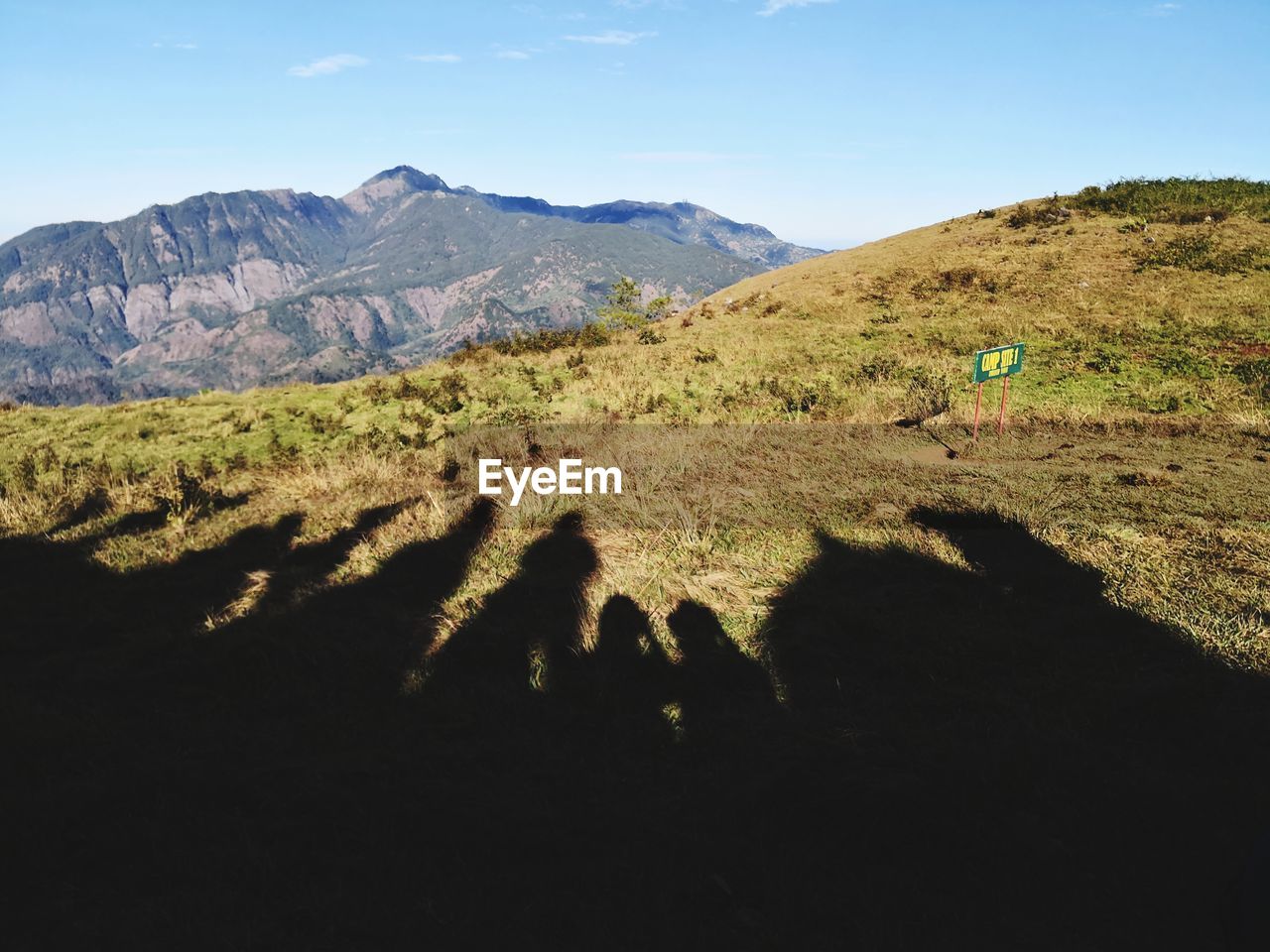 SHADOW OF PEOPLE ON LANDSCAPE AGAINST SKY