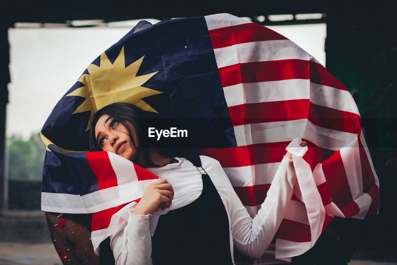Thoughtful female model posing with malaysian flag on spool