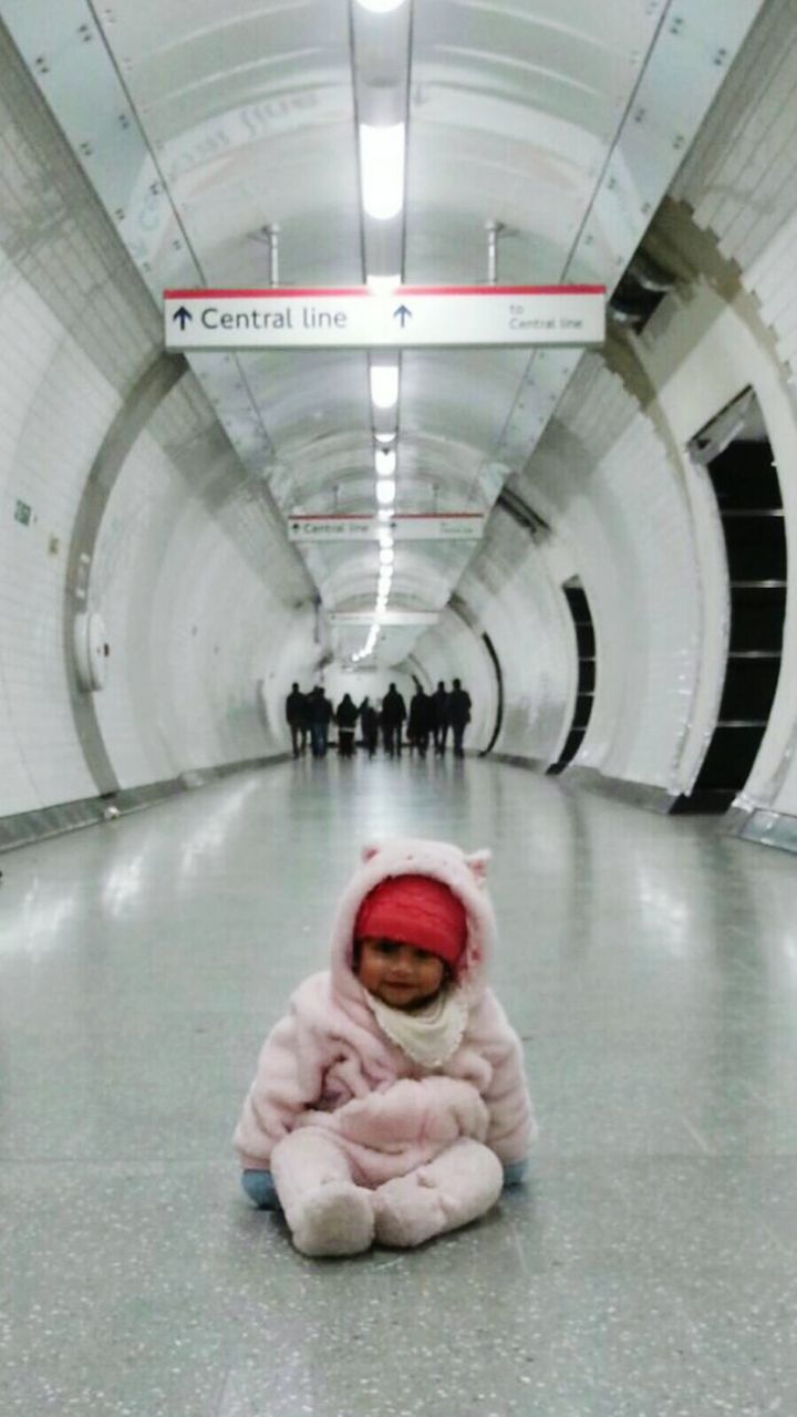 Portrait of baby sitting on floor at subway station