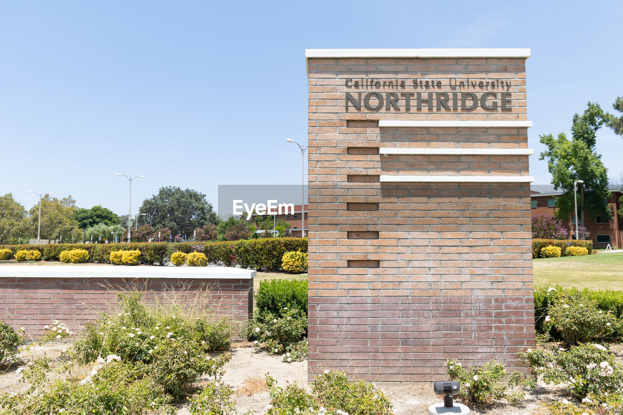 architecture, plant, nature, built structure, sky, text, tree, clear sky, building exterior, day, landmark, no people, estate, travel destinations, sunny, western script, memorial, communication, outdoors, blue, travel, history, the past, building