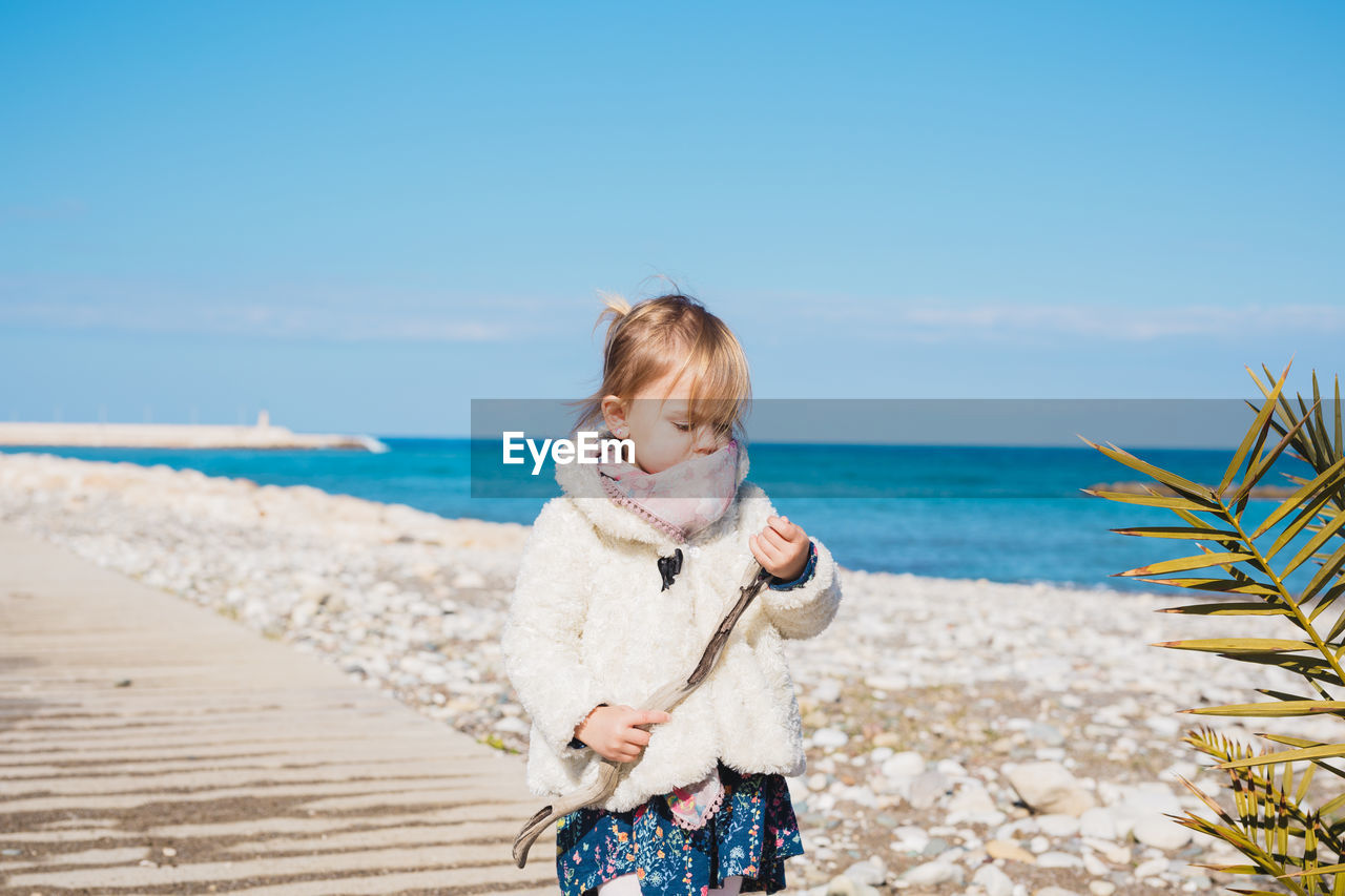 Boy standing on beach against sky