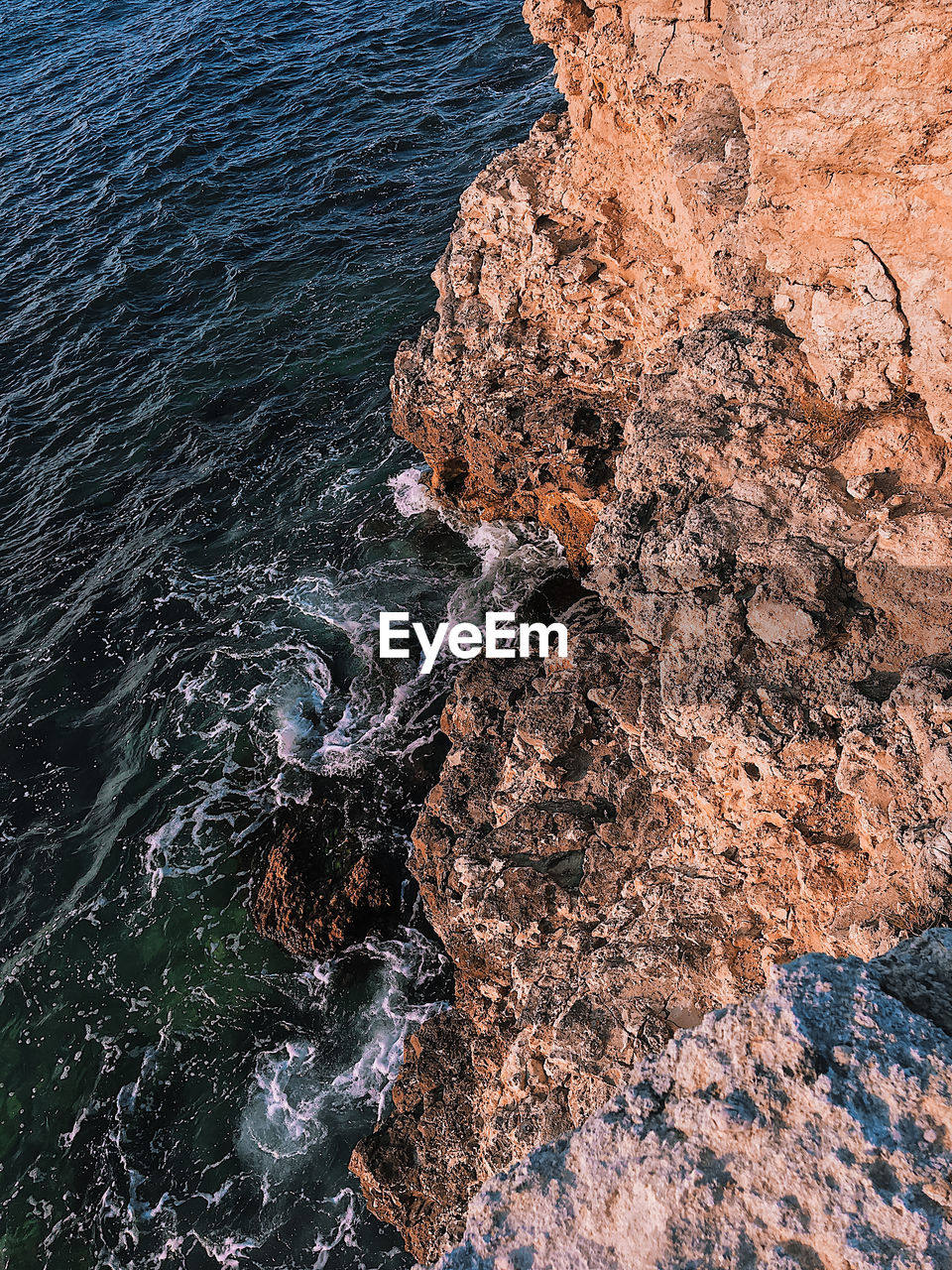 View from the top to the deep of the sea, the water beats on the stones, wave-like background