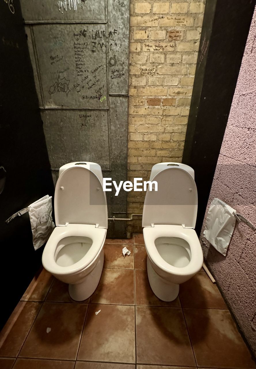 toilet, bathroom, toilet bowl, hygiene, room, domestic bathroom, floor, bidet, convenience, plumbing fixture, home, domestic room, flooring, public building, indoors, flushing toilet, urinal, public restroom, tile, restroom, lid, seat, no people, household fixture, tiled floor, architecture, toilet seat, neat, toilet paper, high angle view