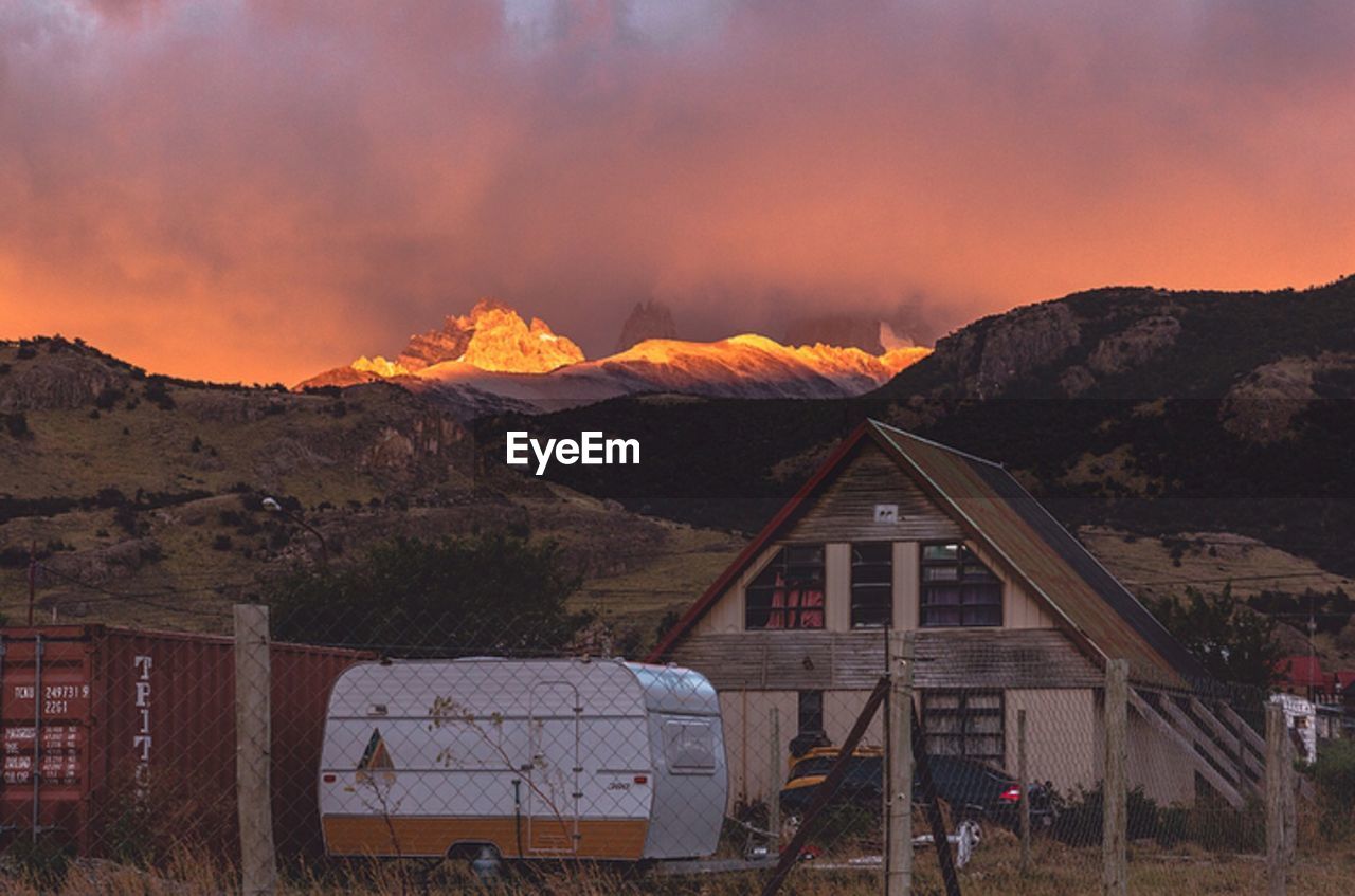 Houses by mountains against sky during sunset