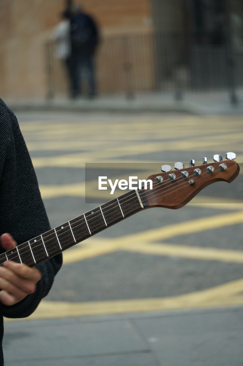 Midsection of man playing guitar