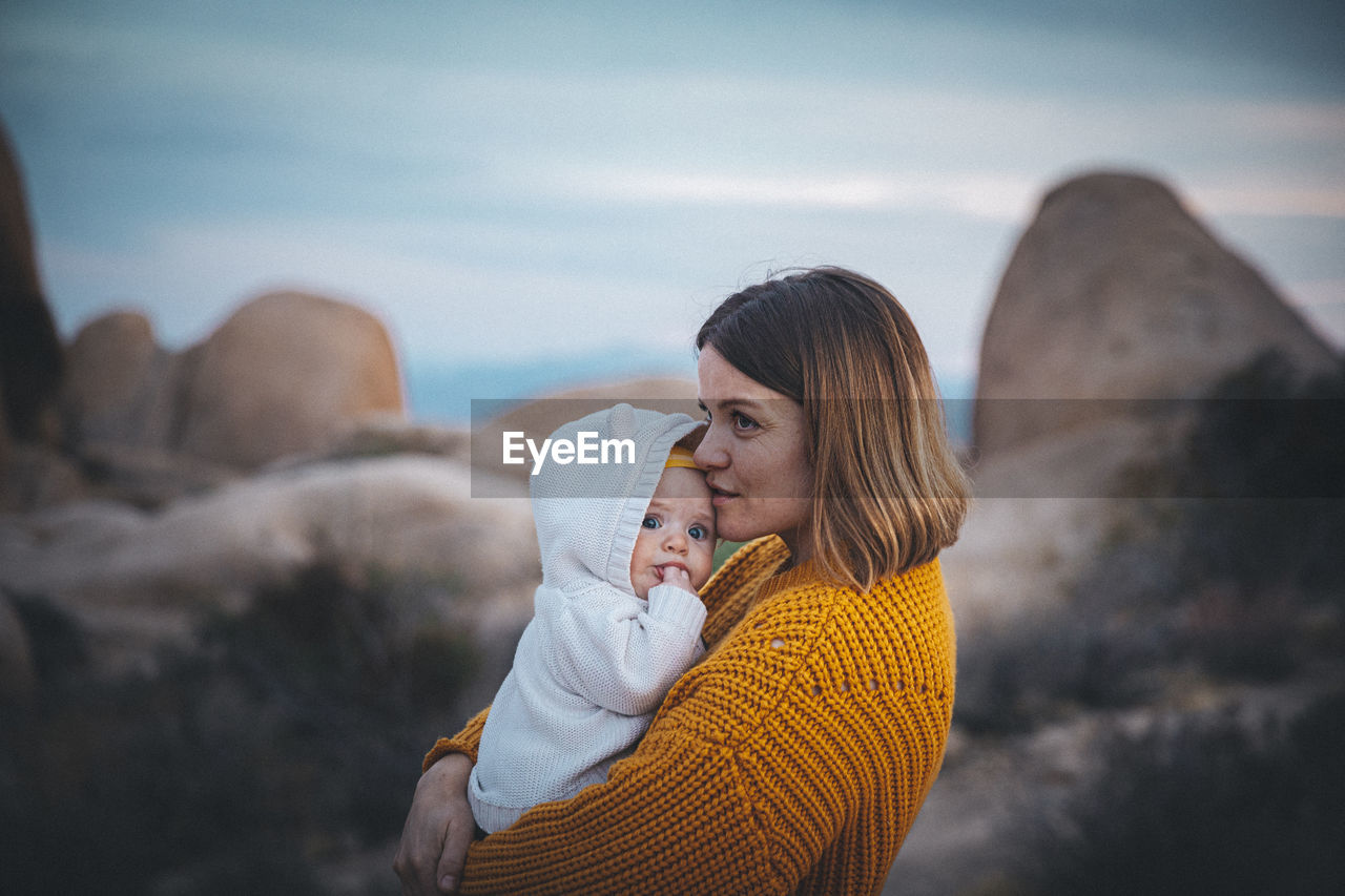 A woman with a baby is standing in a desert of california