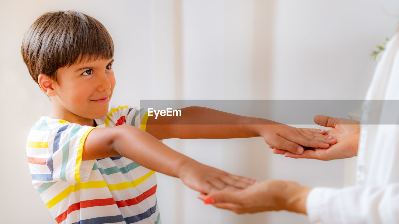 Physical medical exam for children. physical therapist doing medical exam, boy holding arms raised