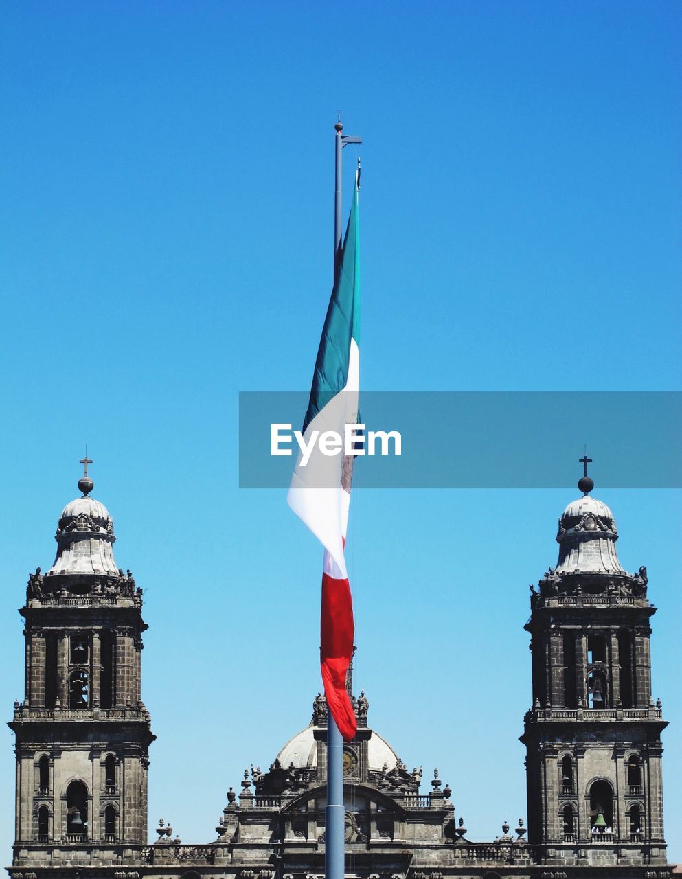 Mexican flag by metropolitan cathedral against clear blue sky