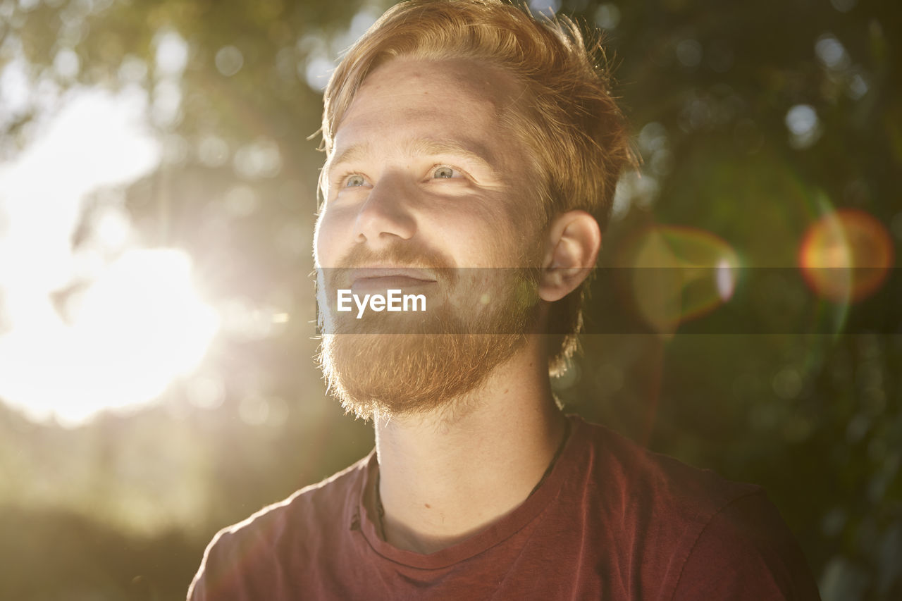 Smiling young man in backlight outdoors