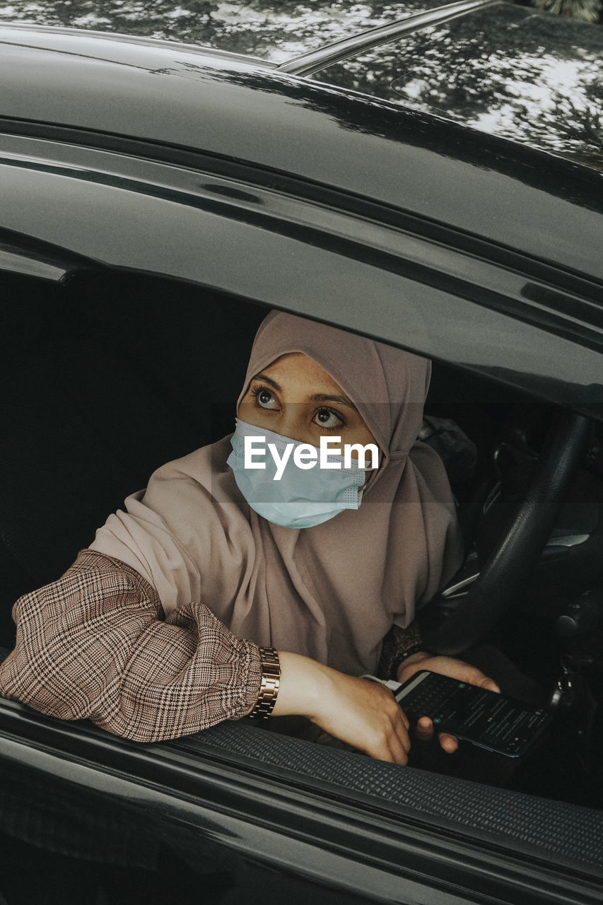 Portrait of young woman sitting in car