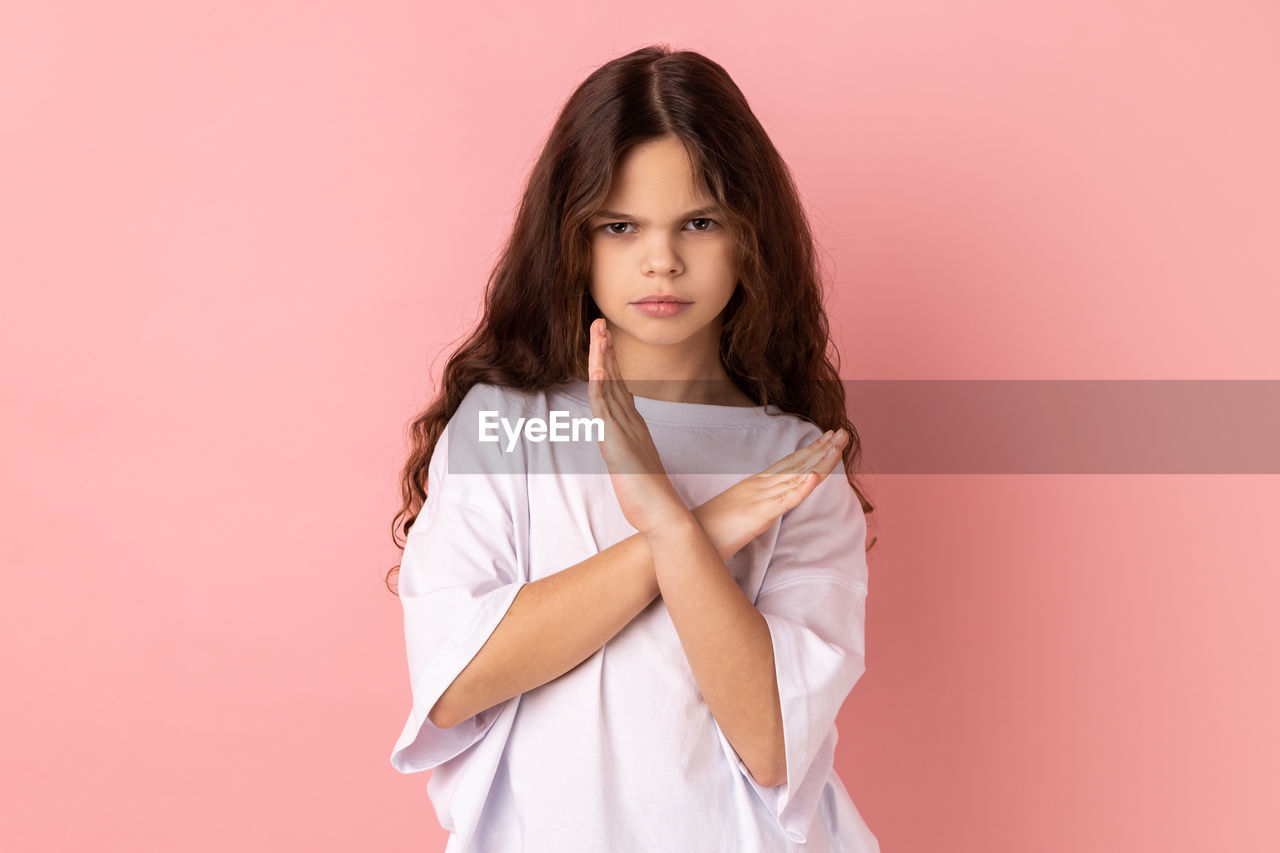 portrait, pink, one person, women, studio shot, looking at camera, long hair, hairstyle, colored background, indoors, brown hair, adult, young adult, pink background, photo shoot, fashion, child, clothing, female, cute, standing, waist up, front view, copy space, emotion, cut out, childhood, human face, dress, serious, sleeve, person, casual clothing, smiling