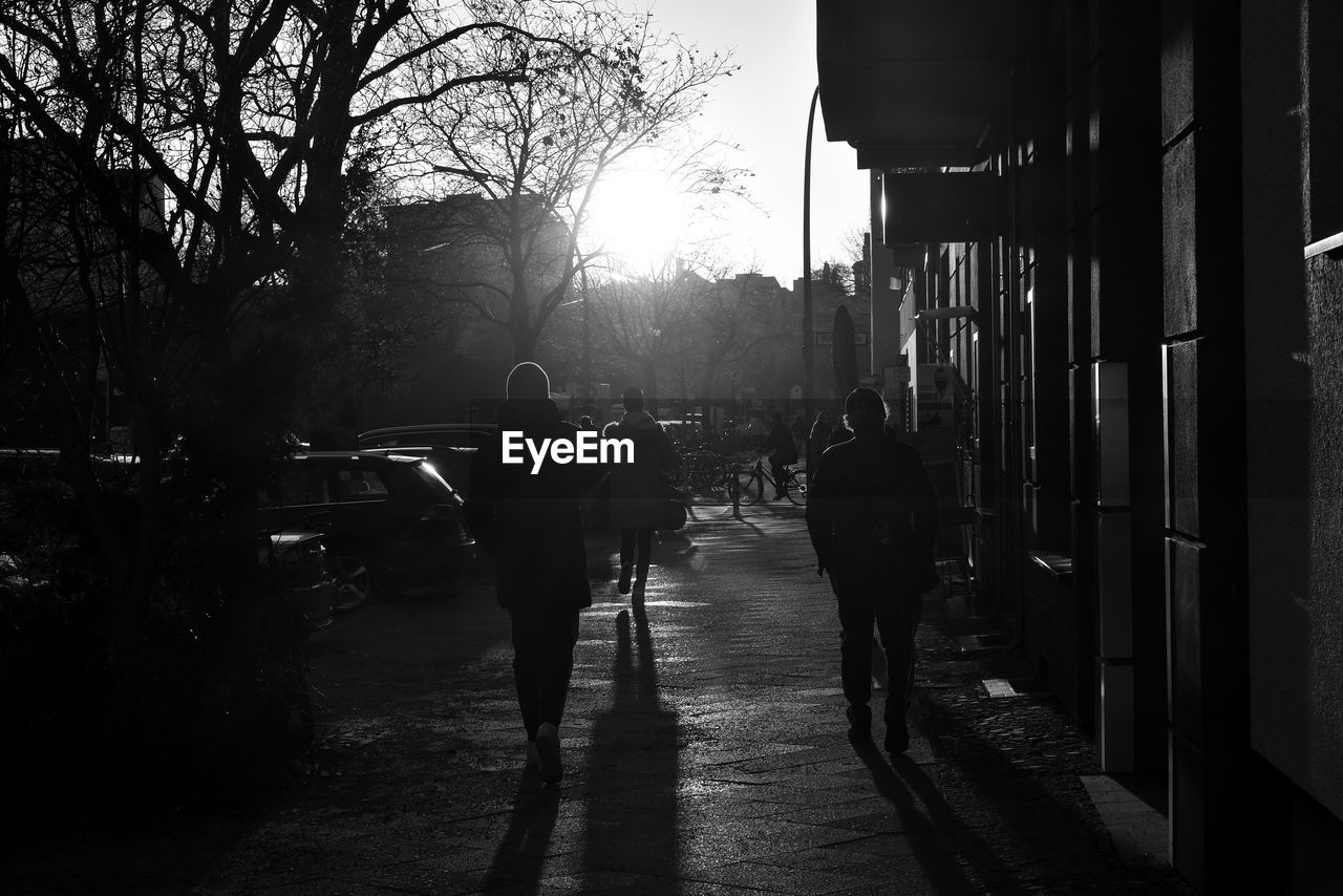 Rear view of silhouette people walking on street in city