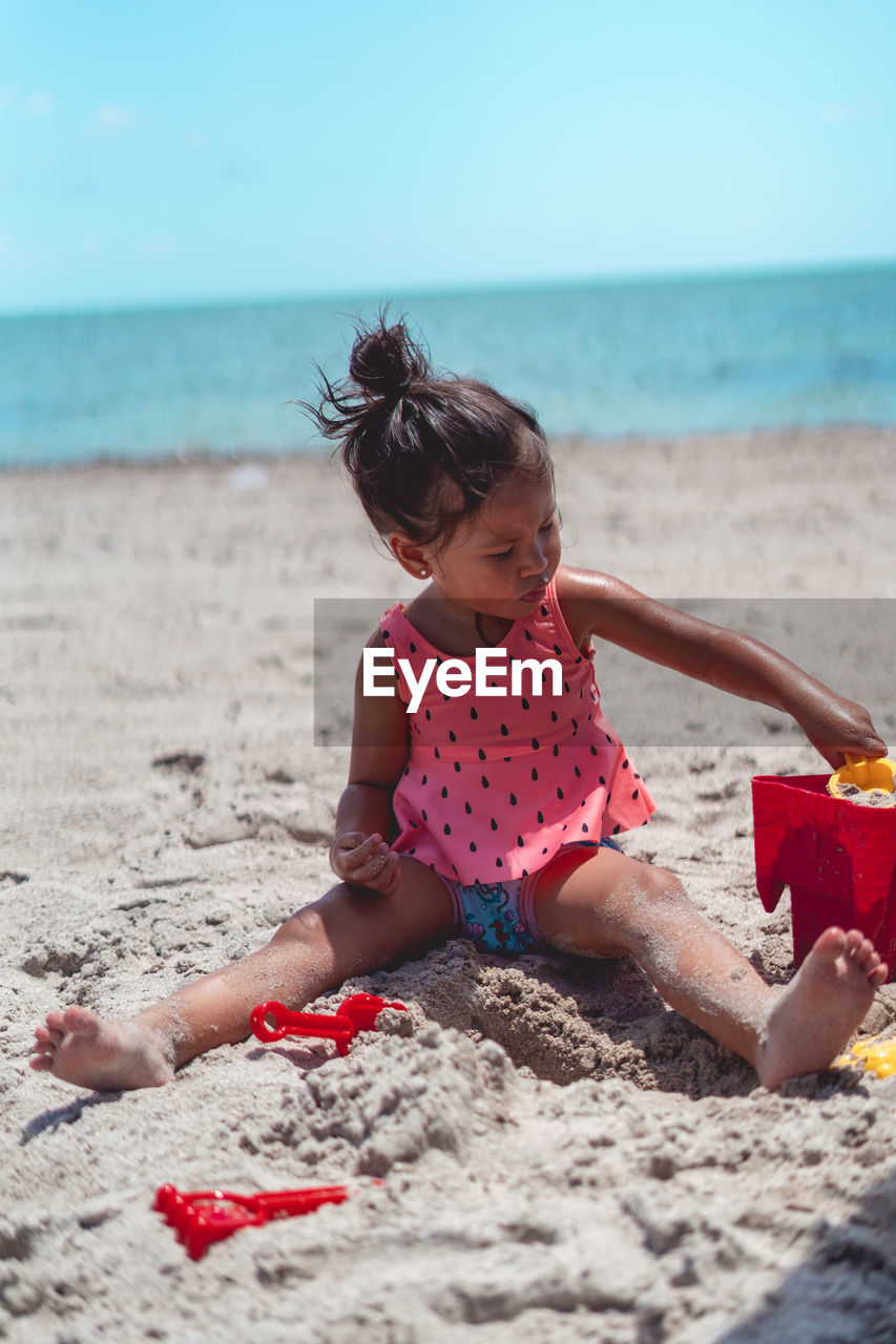 Front view of girl sitting on sand at beach