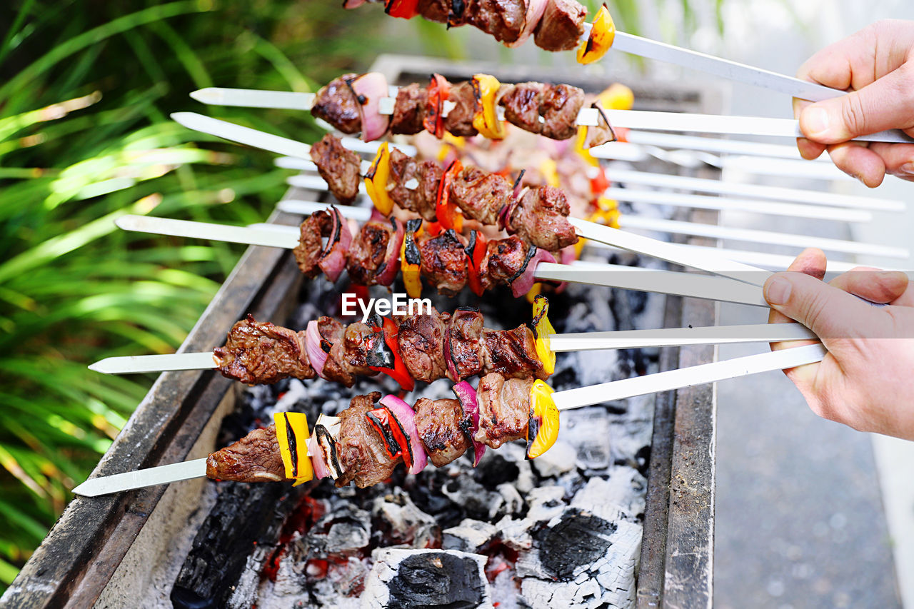 MIDSECTION OF PERSON PREPARING FOOD ON BARBECUE