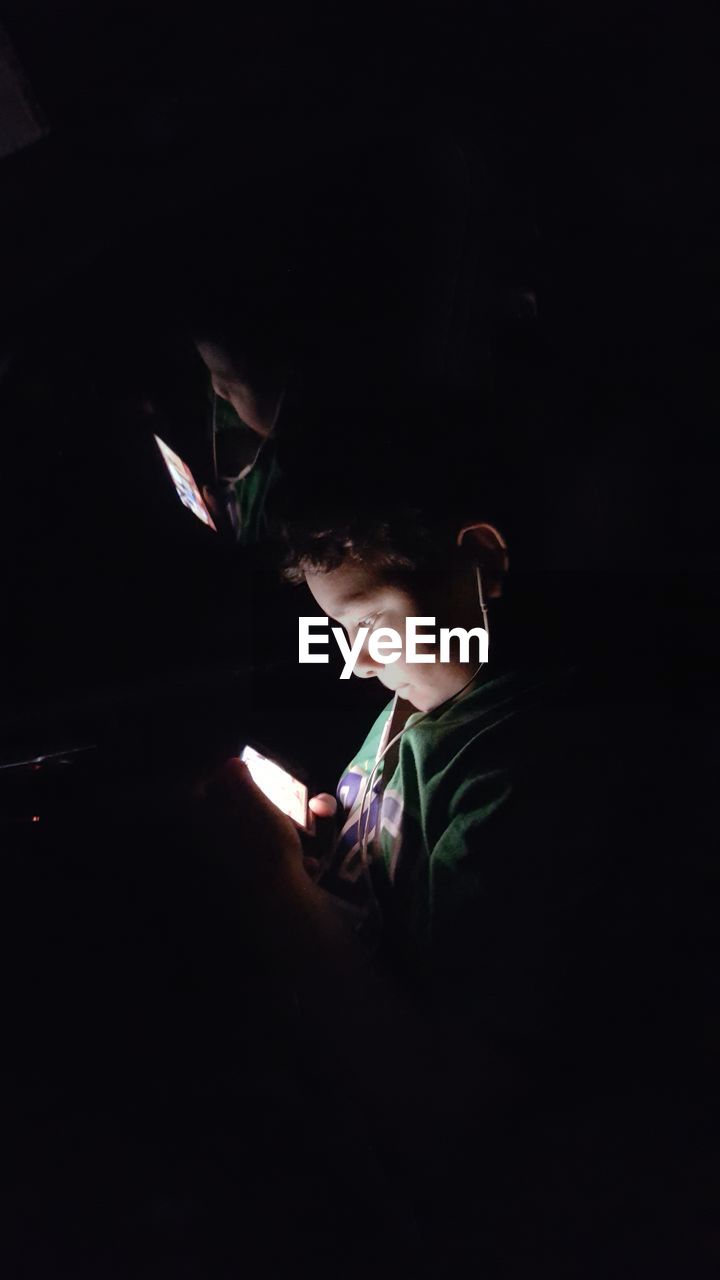 Boy using mobile phone in darkroom
