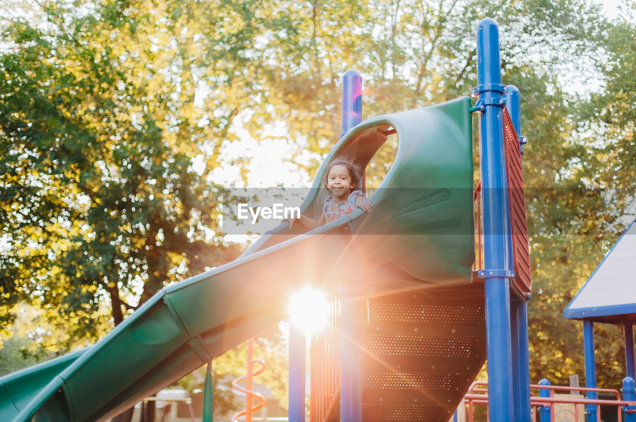 Diverse mixed race pre school girl outdoors during summer having fun at playground park 