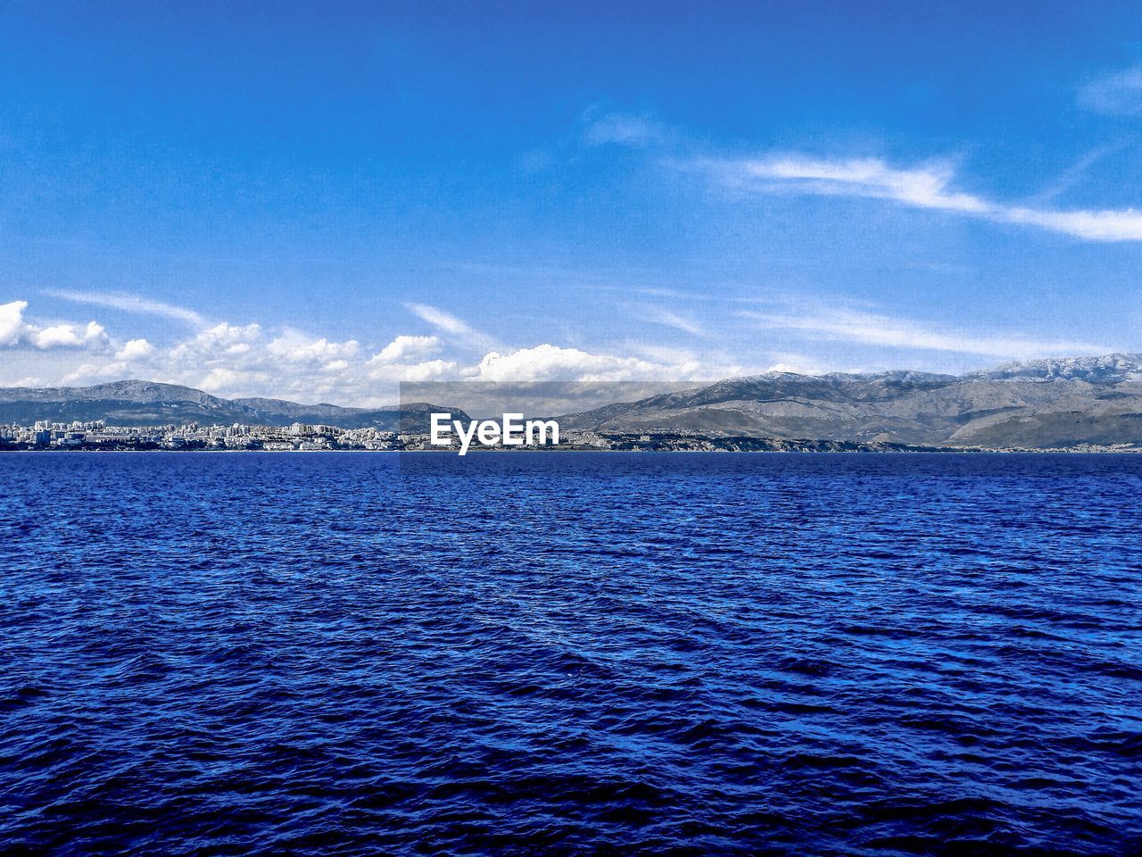 SCENIC VIEW OF SEA BY MOUNTAIN AGAINST BLUE SKY