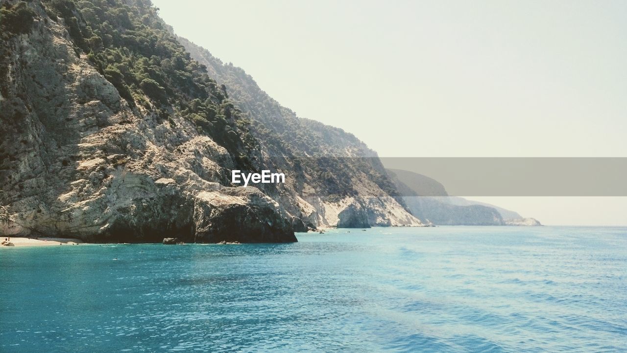 SCENIC VIEW OF SEA AND MOUNTAINS AGAINST CLEAR SKY