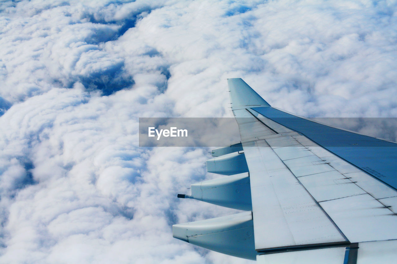 View of airplane wing flying over clouds