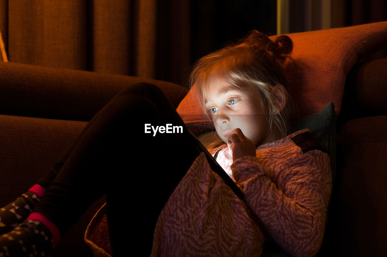 Portrait of girl using digital tablet on sofa