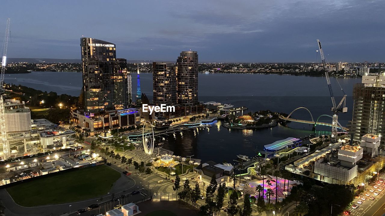 HIGH ANGLE VIEW OF RIVER AMIDST ILLUMINATED BUILDINGS IN CITY