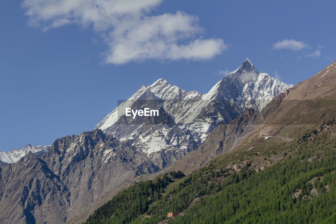 Snow capped rothorn summit view with snow from zermatt valley with typical swiss wooden chalet house