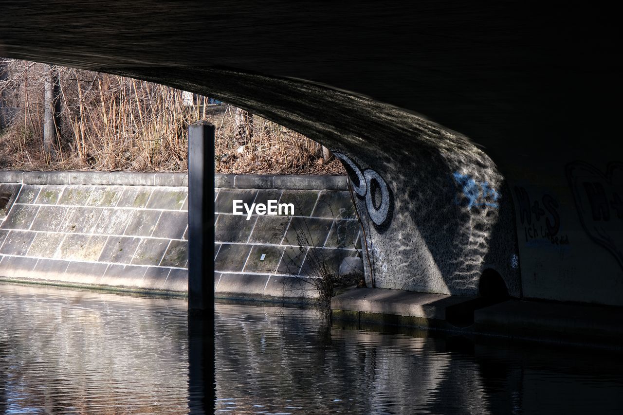 ARCH BRIDGE IN RIVER AGAINST WALL