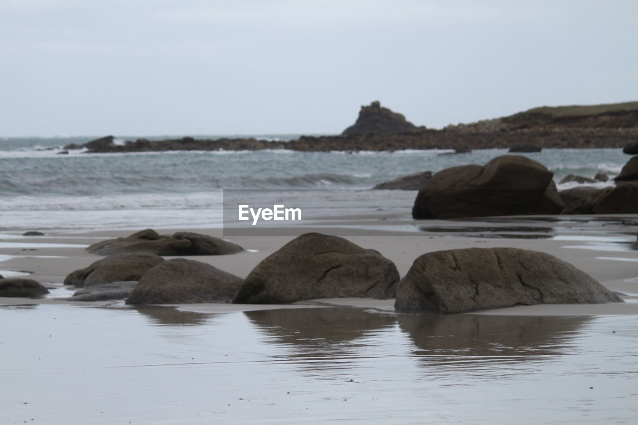 SCENIC VIEW OF ROCKS ON BEACH AGAINST SKY