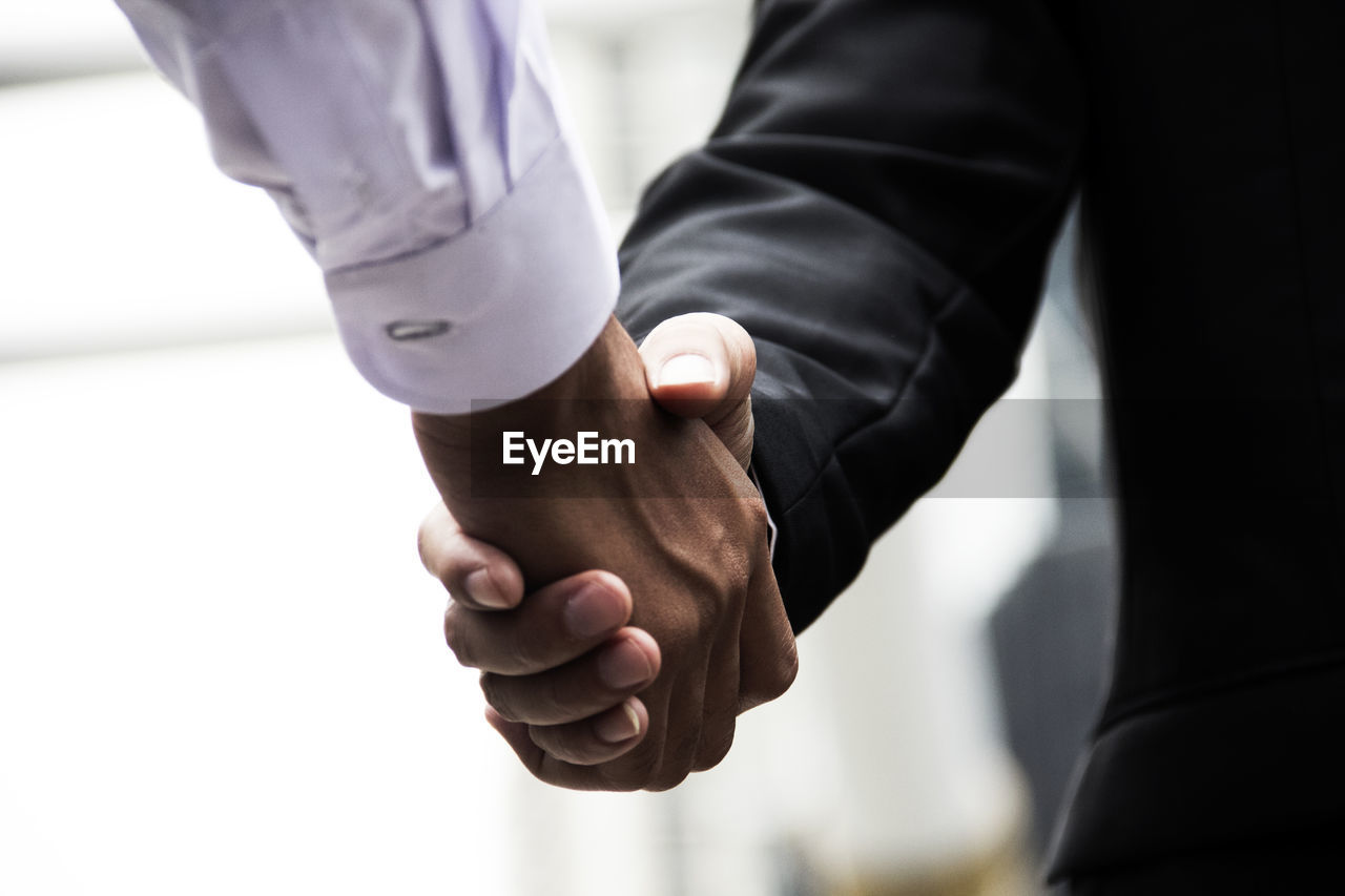 Midsection of business people giving handshake at office