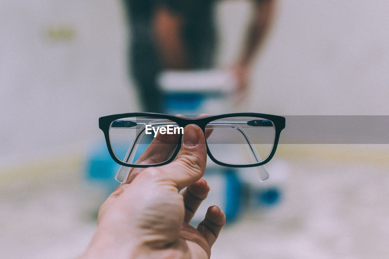 Cropped hand of person holding eyeglasses