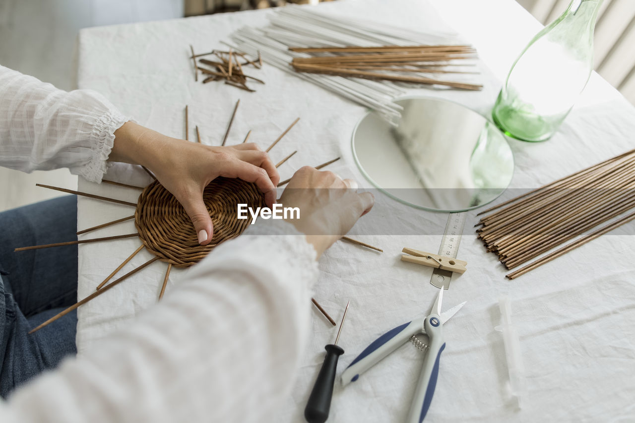 Mature woman making paper vine basket at home