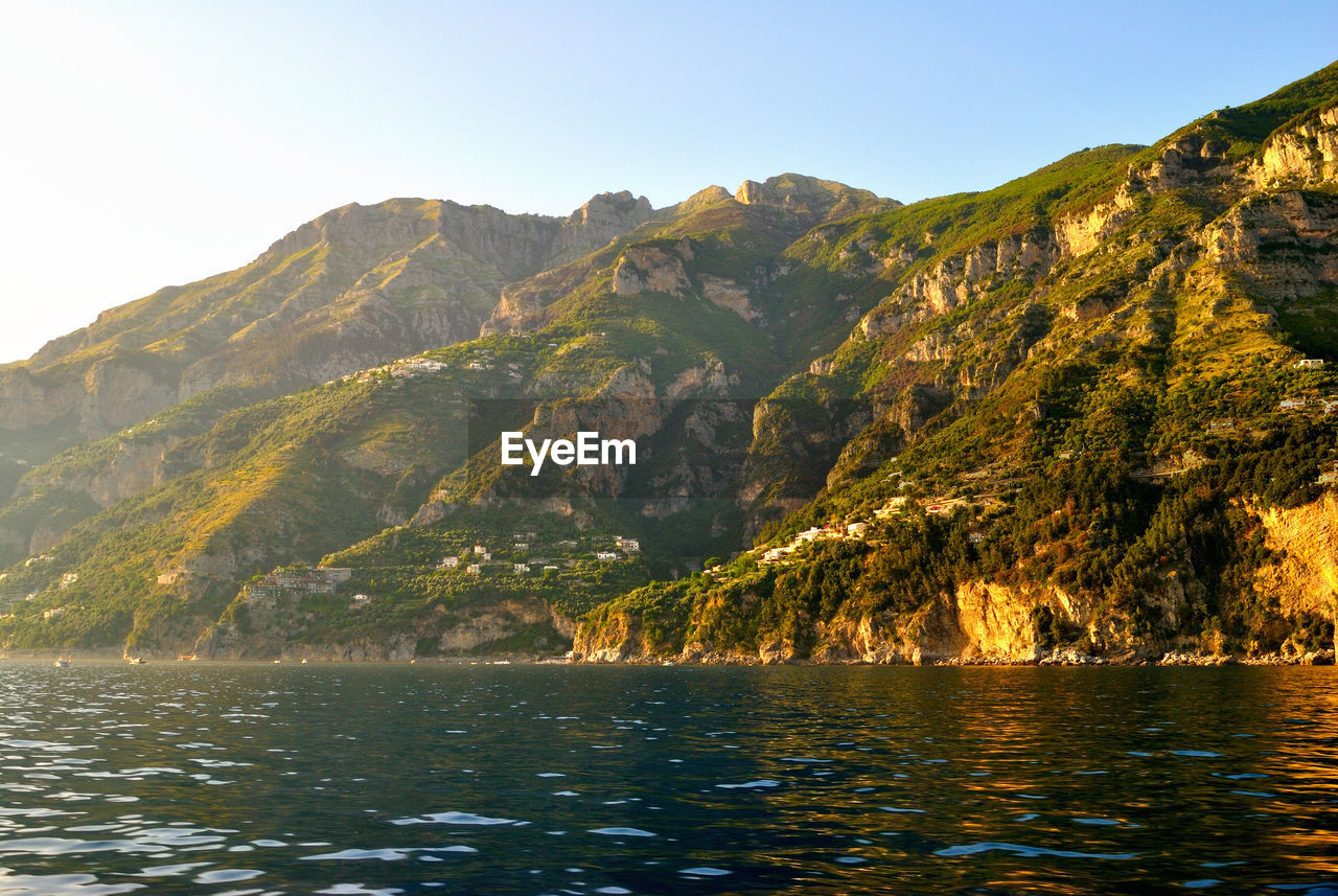 Scenic view of sea and mountains against clear sky