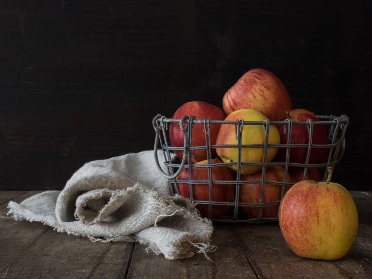 Close-up of apples in basket on table against black background