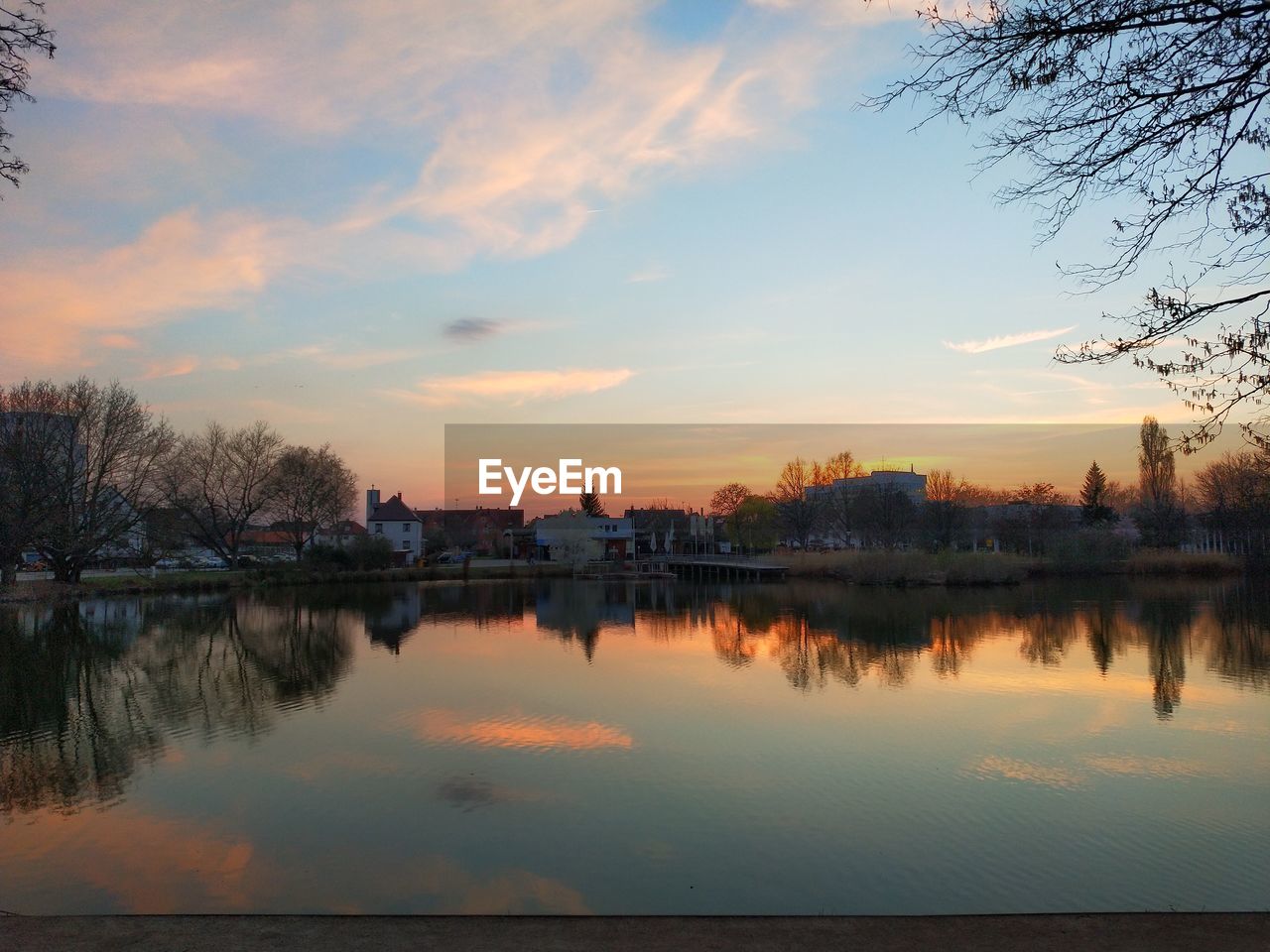 SCENIC VIEW OF LAKE AGAINST BUILDINGS DURING SUNSET