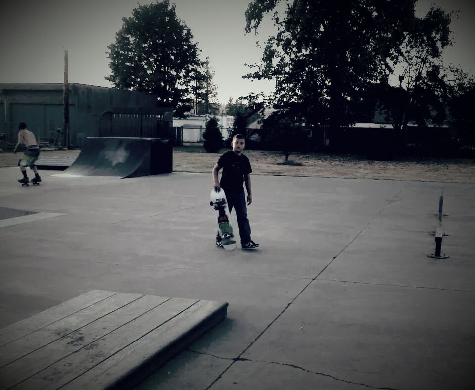 Portrait of young man with skateboard walking on road