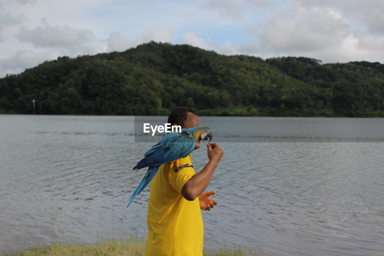 rear view of woman standing by lake against mountain