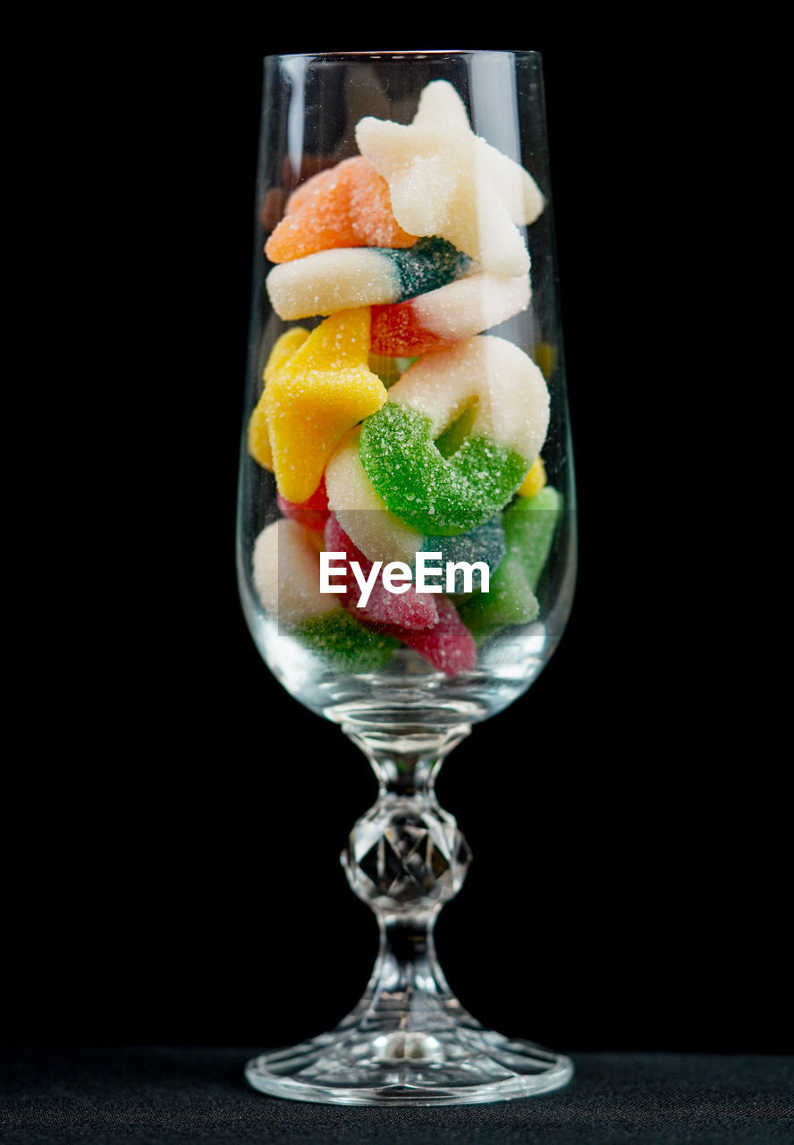 Close-up of sweet food in wineglass against black background