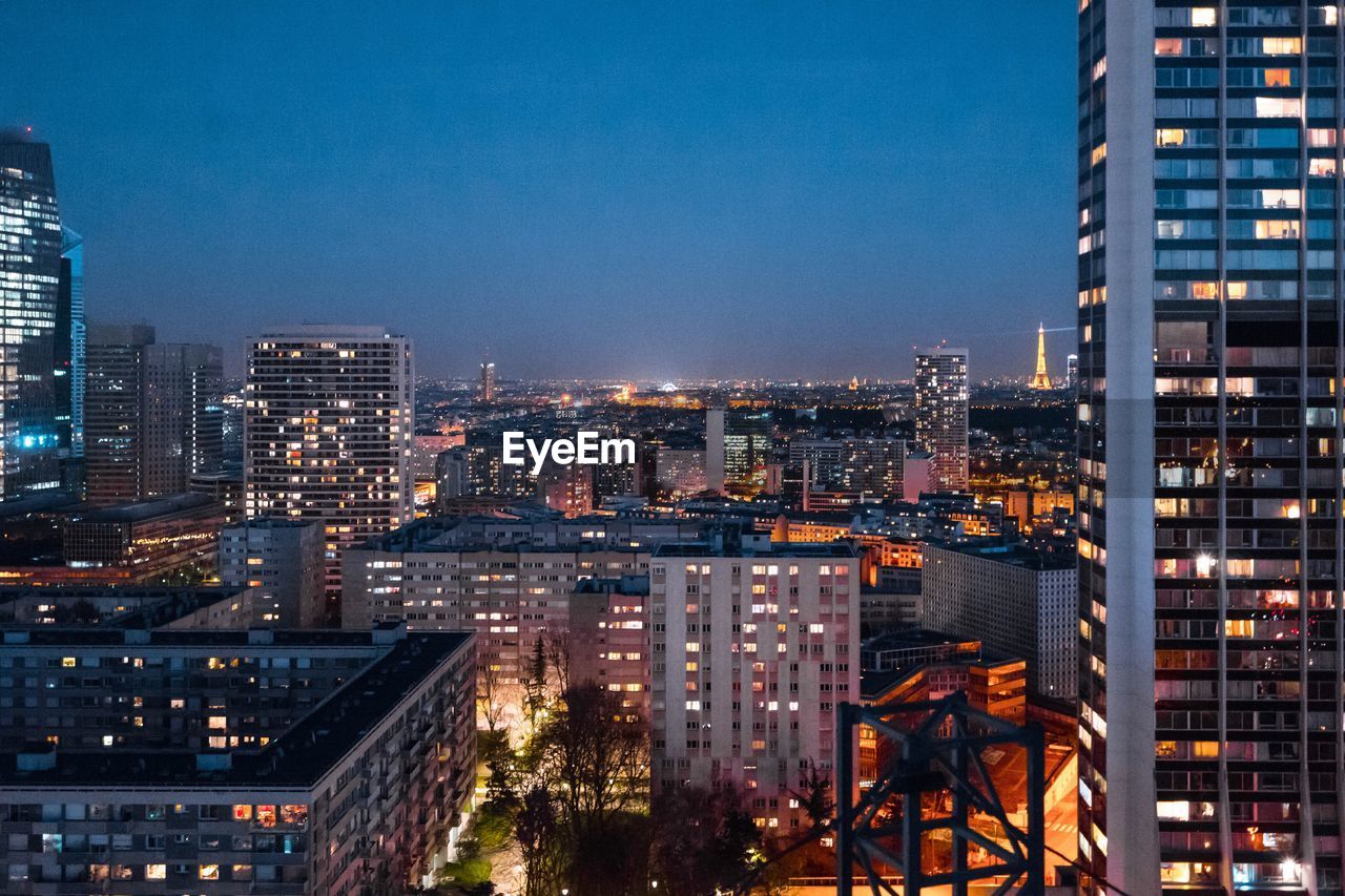 ILLUMINATED CITYSCAPE AGAINST CLEAR SKY