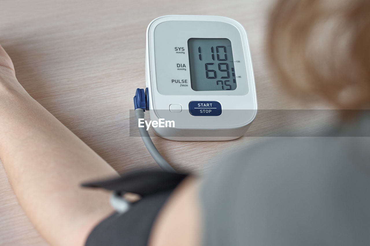 Midsection of woman with blood pressure gauge on table