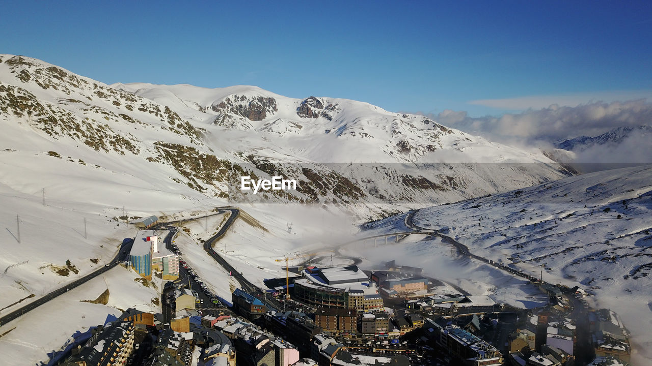Scenic view of ski resort with snowcapped mountains against clear sky 