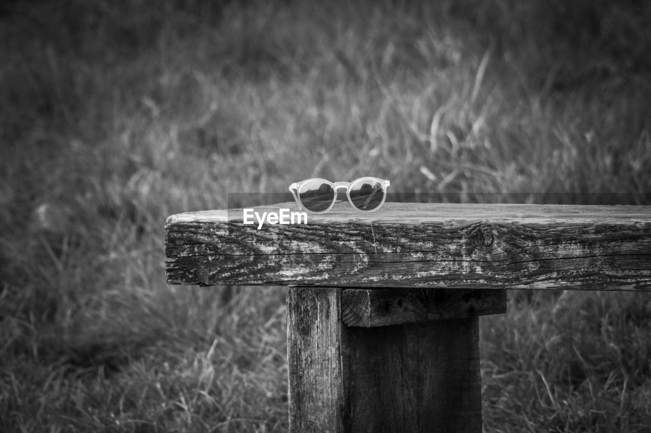 Close-up of sunglasses on wooden bench 