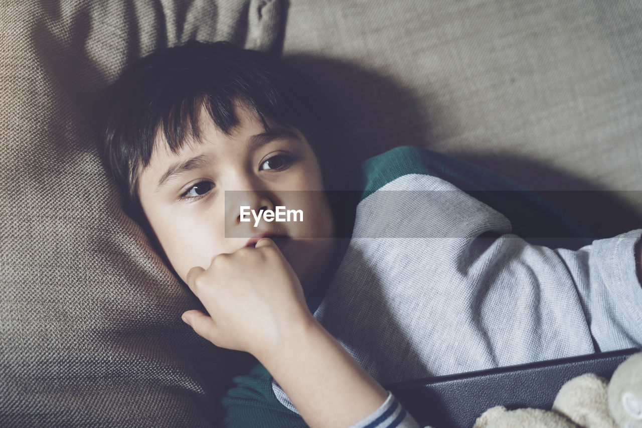 High angle view of cute boy lying on sofa