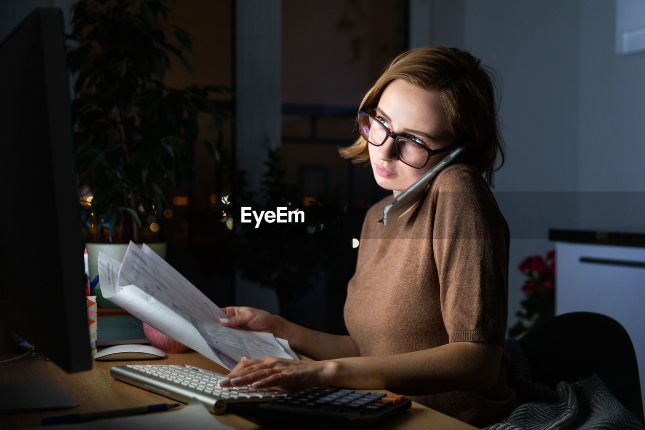 Businesswoman using mobile phone while working at home