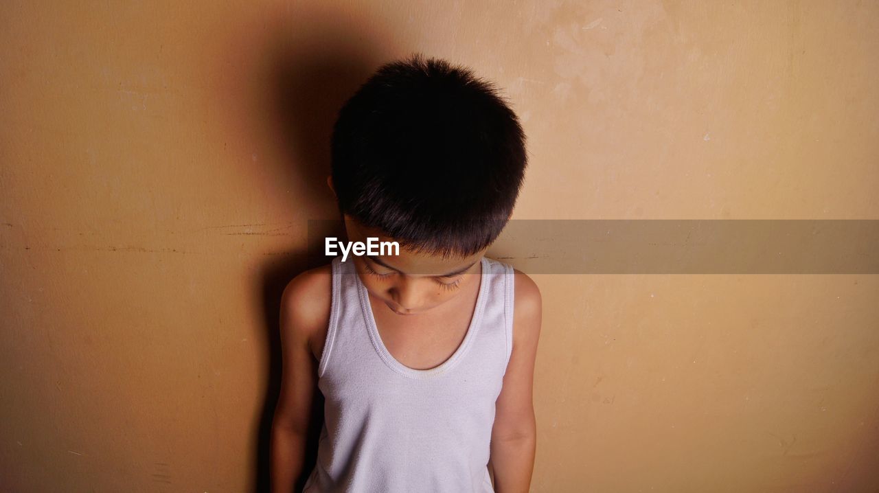 Boy standing against wall at home
