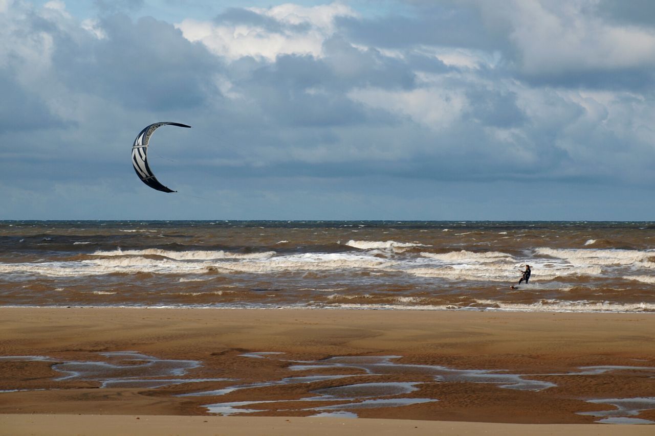 Person kiteboarding at beach against sky
