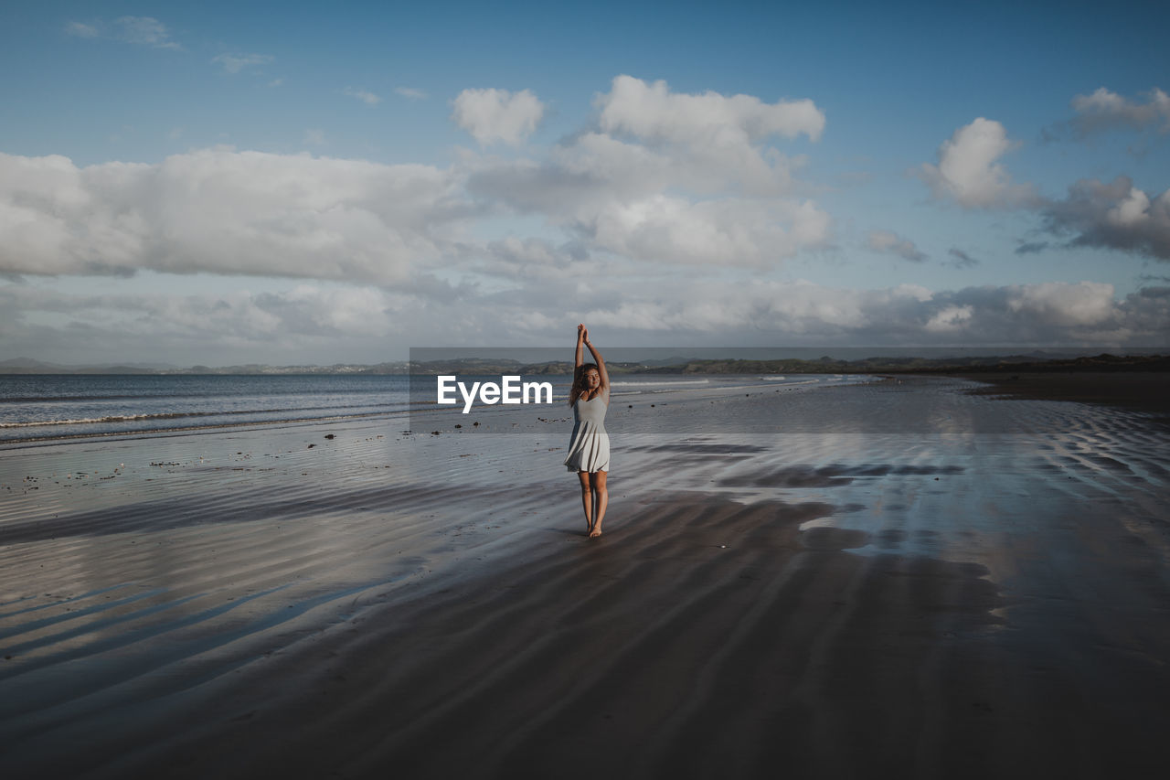 Woman standing at beach against sky