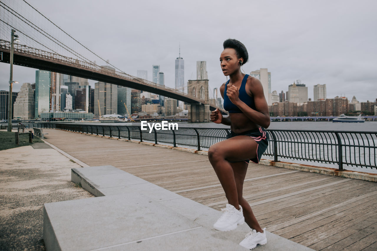 Woman exercising on bridge in city